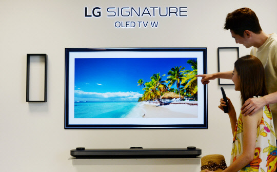 LG전자는 여행정보 사이트 '트립어드바이저'와 손잡고 올레드 TV와 슈퍼 울트라 고화질(HD) TV 갤러리 애플리케이션에 계절별 추천 여행지 사진을 추가 제공한다고 27일 밝혔다. 모델들이 LG 시그니처 OLED TV W를 소개하고 있다. <LG전자 제공>